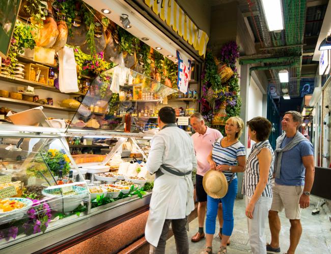 group of mature travellers conversing at a European market stall
