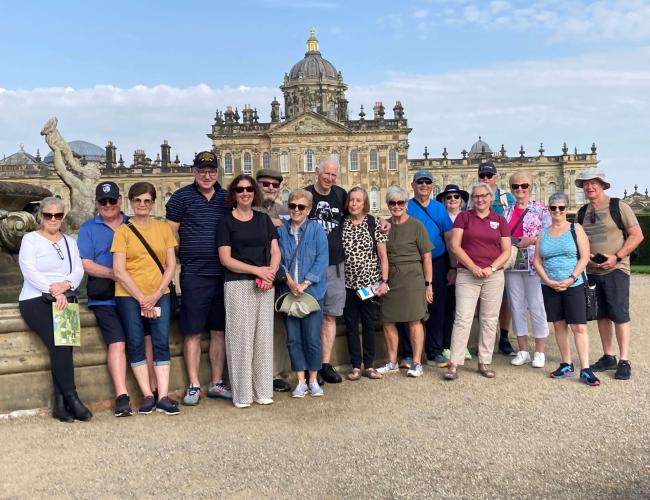 Group of mature adults standing together in front of British monument