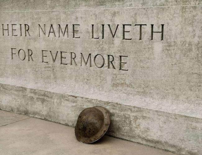 WWI monument with 'their name liveth for evermore' etched into stone with helmet leaning against it
