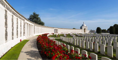 Tyne Cot Commonwealth War Graves Cemetery, Ypres, with blue sky and red flowers