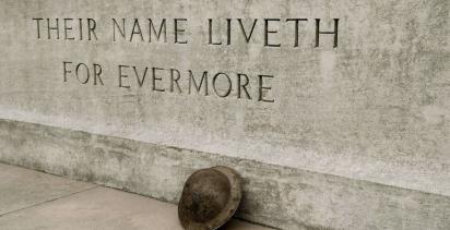WWI monument with 'their name liveth for evermore' etched into stone with helmet leaning against it
