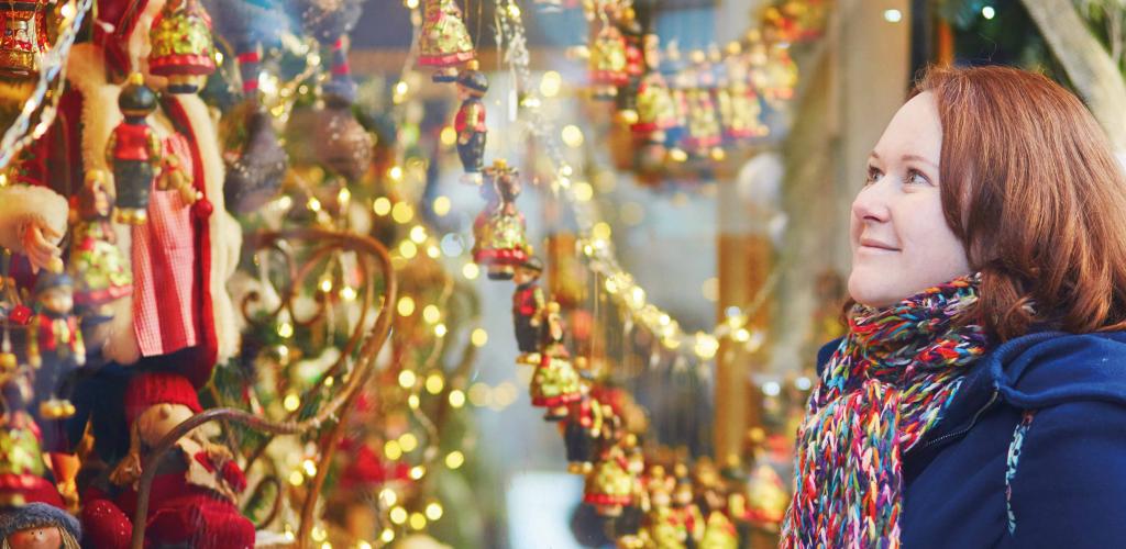 mature woman looking through a shop window at Christmas lights