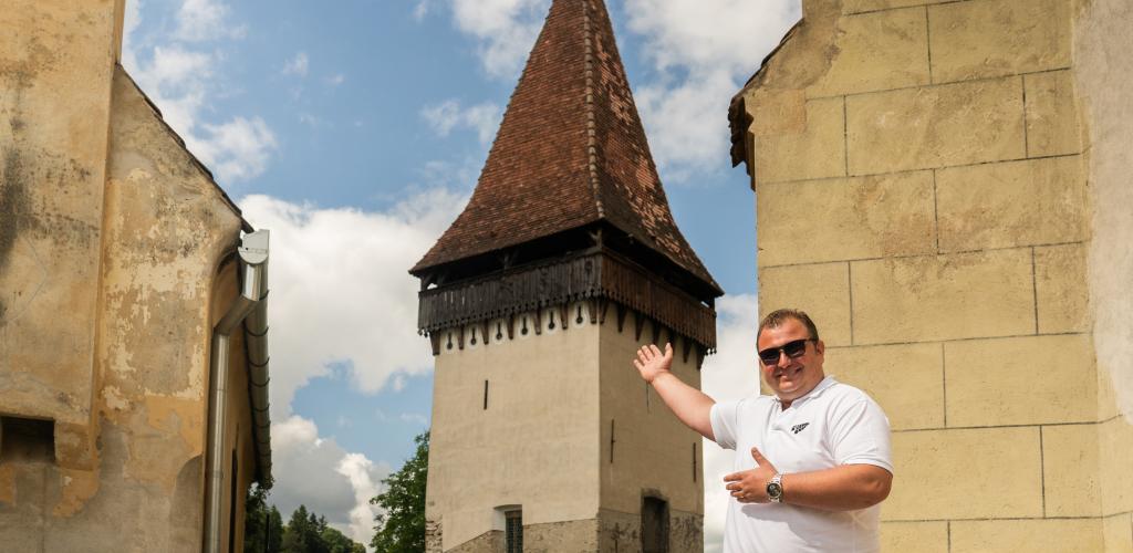 Man in welcoming pose with historic town backdrop