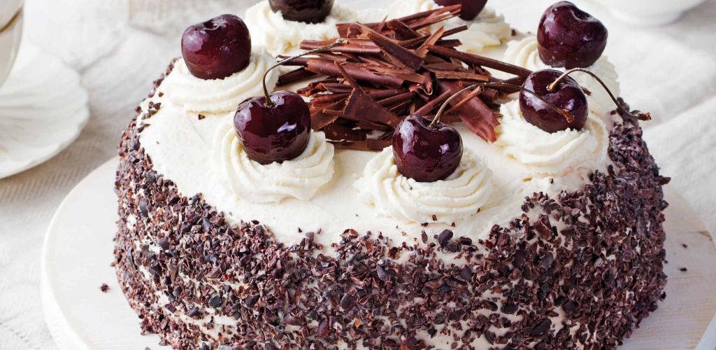 cherry topped black forest gateau cake on a set table