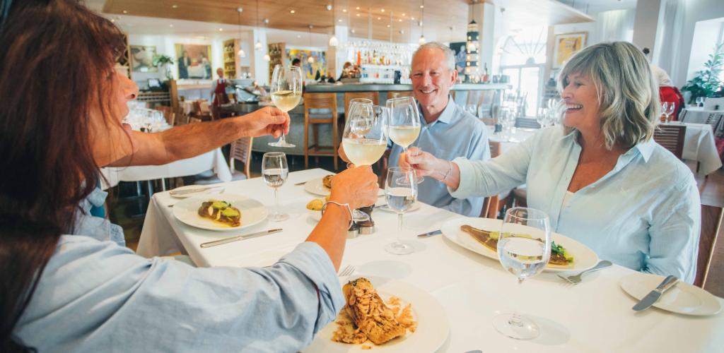 group of mature travellers clinking wine glasses over a table at Rick Stein's restaurant