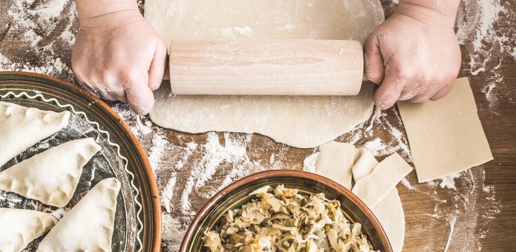 baker rolling out dough for polish dumplings