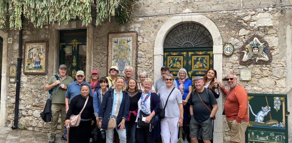group posing outside old Sicilian building