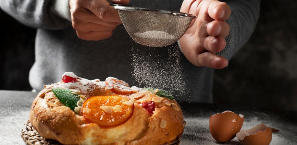 man sprinkling icing sugar over a traditional cake
