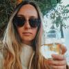 young blonde woman wearing sunglasses and holding a glass of white wine